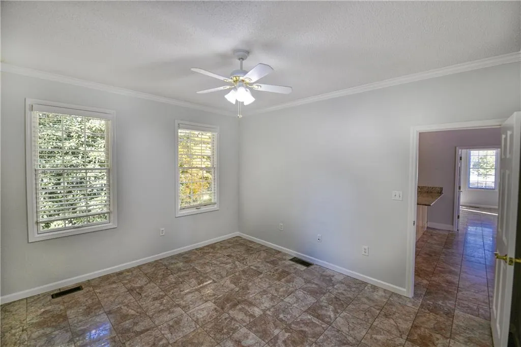 Unfurnished room featuring a wealth of natural light, visible vents, crown molding, and ceiling fan