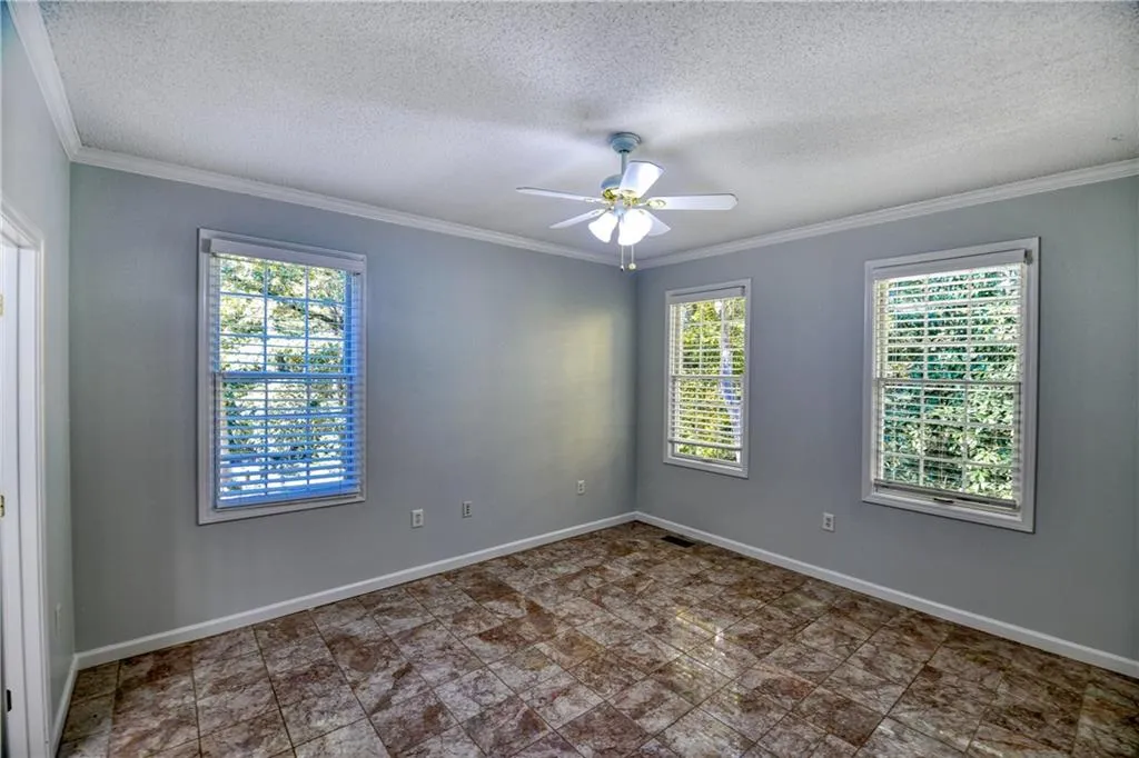 Spare room featuring baseboards, crown molding, ceiling fan, and a textured ceiling