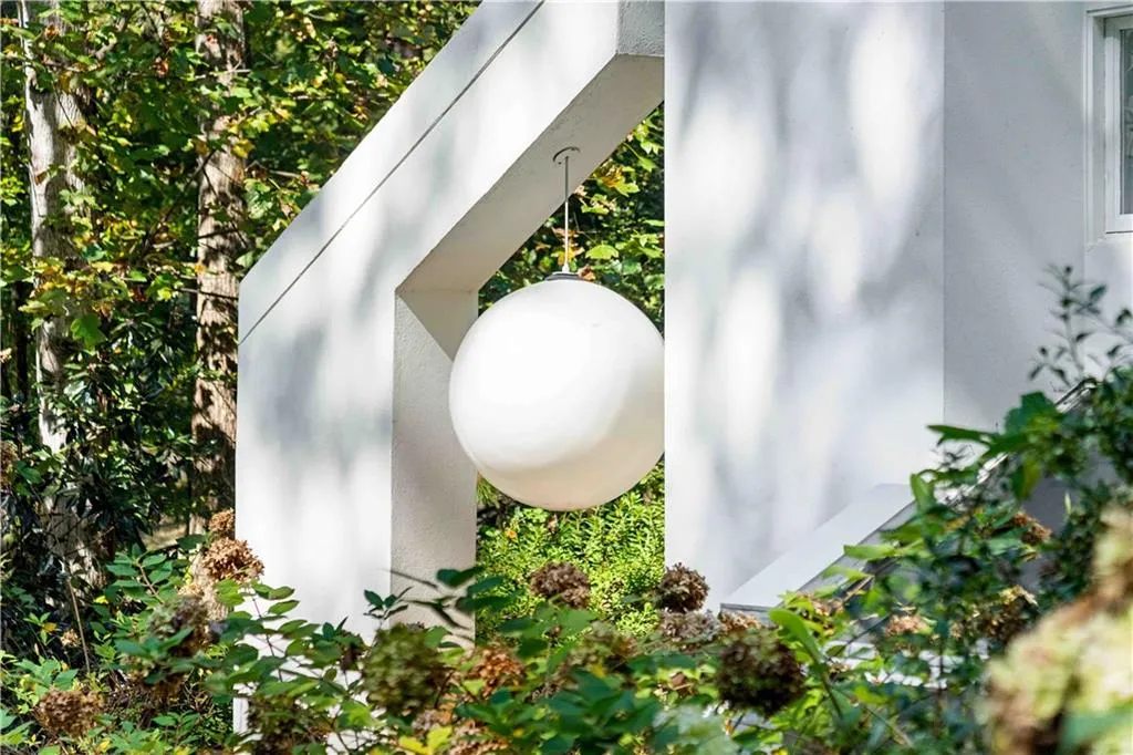 Architectural white stucco entryway featuring a geometric angular frame and a spherical pendant light fixture