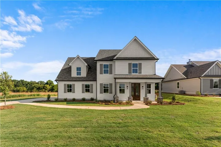 Two-story residence with a covered front porch featuring stone-clad columns, horizontal siding, and dark shutters