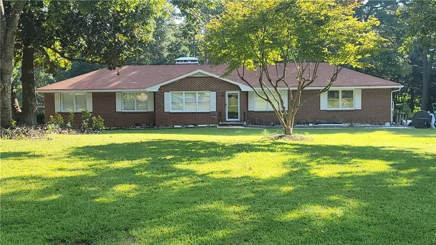 Brick exterior residence with a red-toned roof, multiple windows, and a prominent front door