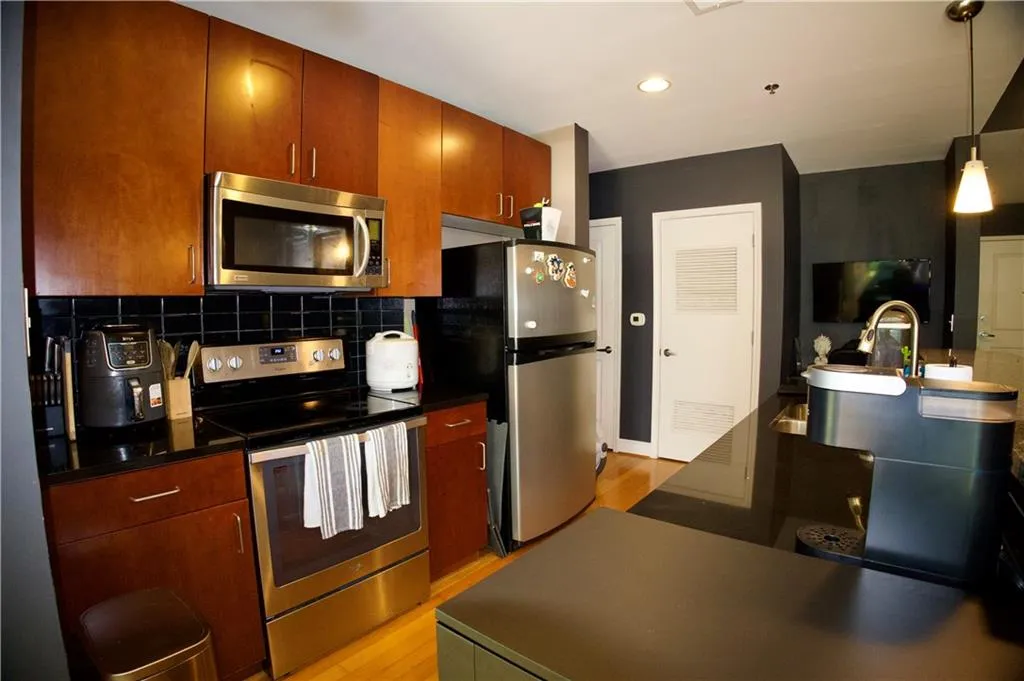 Kitchen with stainless steel appliances, light wood-type flooring, backsplash, hanging light fixtures, and recessed lighting