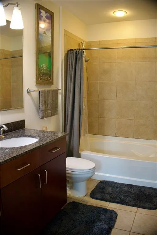 Full bathroom featuring light tile patterned floors, shower / bath combo with shower curtain, and vanity