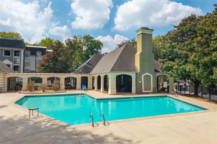 Outdoor pool with surrounding concrete patio and a covered cabana area featuring arched openings