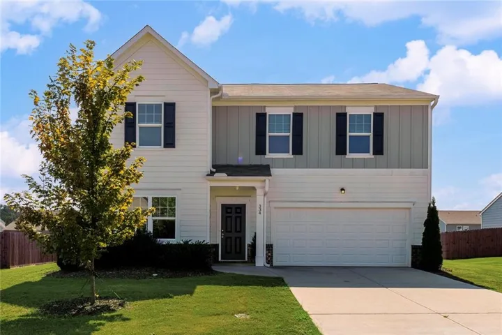 Two-story exterior with a mixed siding facade, attached two-car garage, and a concrete driveway