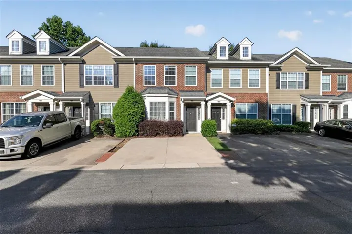 Charming townhome community featuring brick and siding exteriors with dormer windows, covered front entries, and manicured landscaping