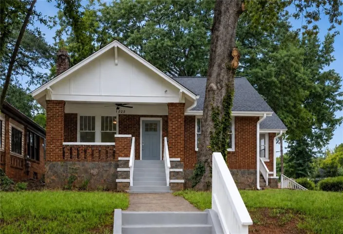 Brick exterior with stone foundation accents, covered front porch, and gabled roofline