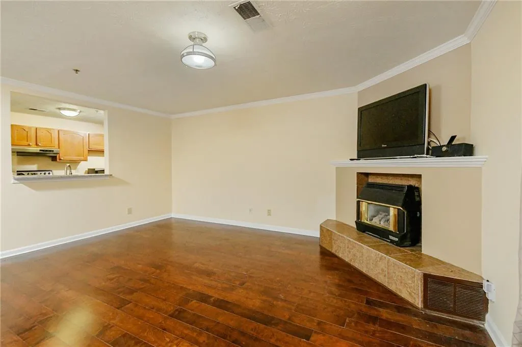 Unfurnished living room featuring visible vents, crown molding, baseboards, a wood stove, and dark wood-style floors