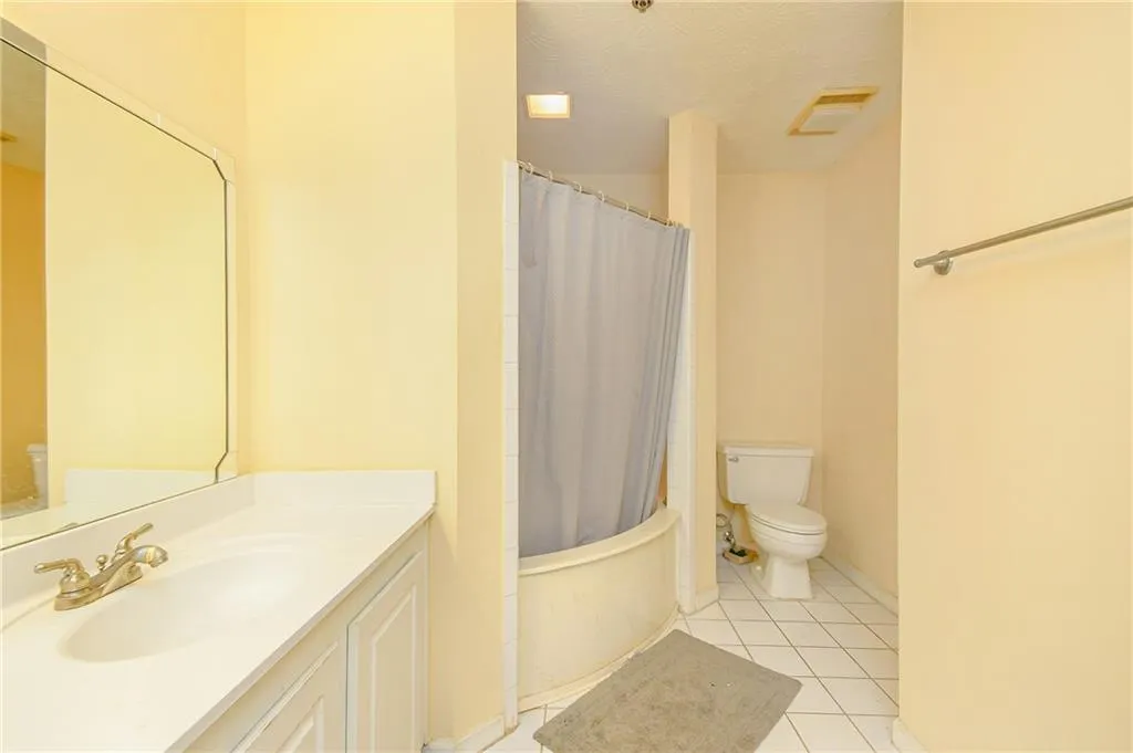 Bathroom with tile patterned flooring, visible vents, toilet, shower / tub combo with curtain, and vanity