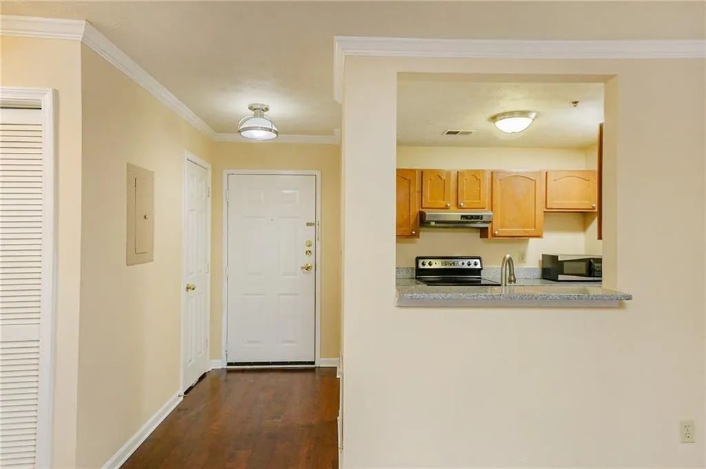 Kitchen featuring visible vents, electric panel, ornamental molding, under cabinet range hood, and appliances with stainless steel finishes