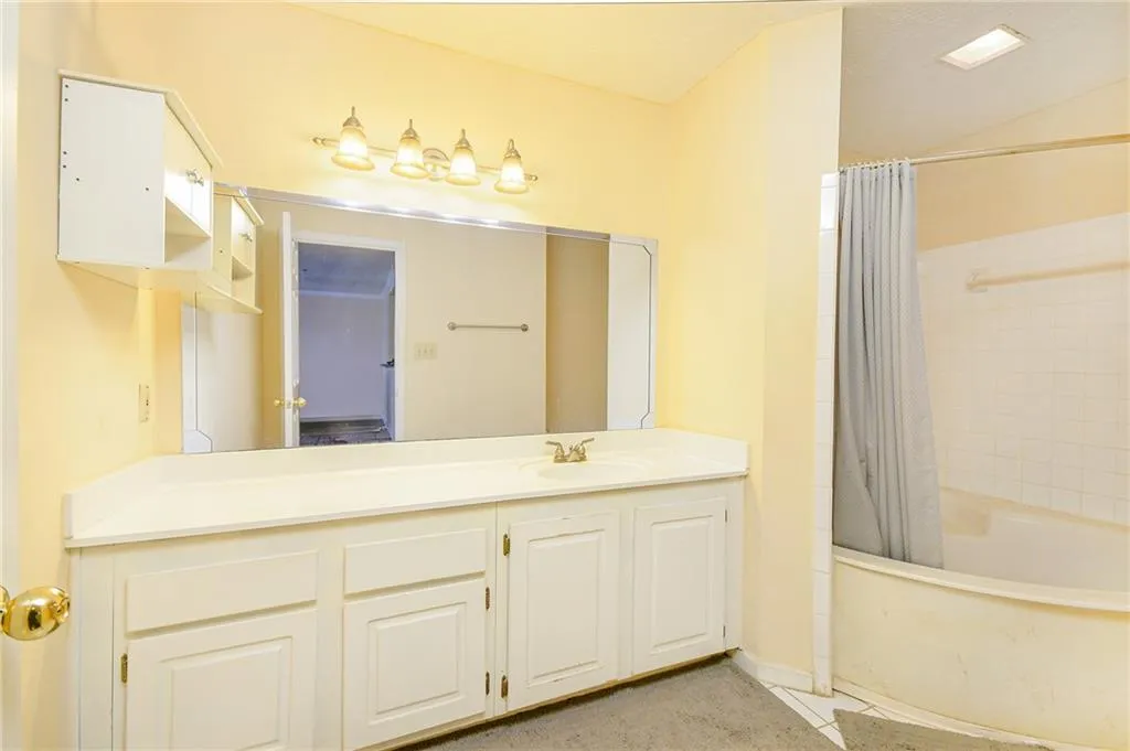 Bathroom featuring vanity and shower / bath combination with curtain