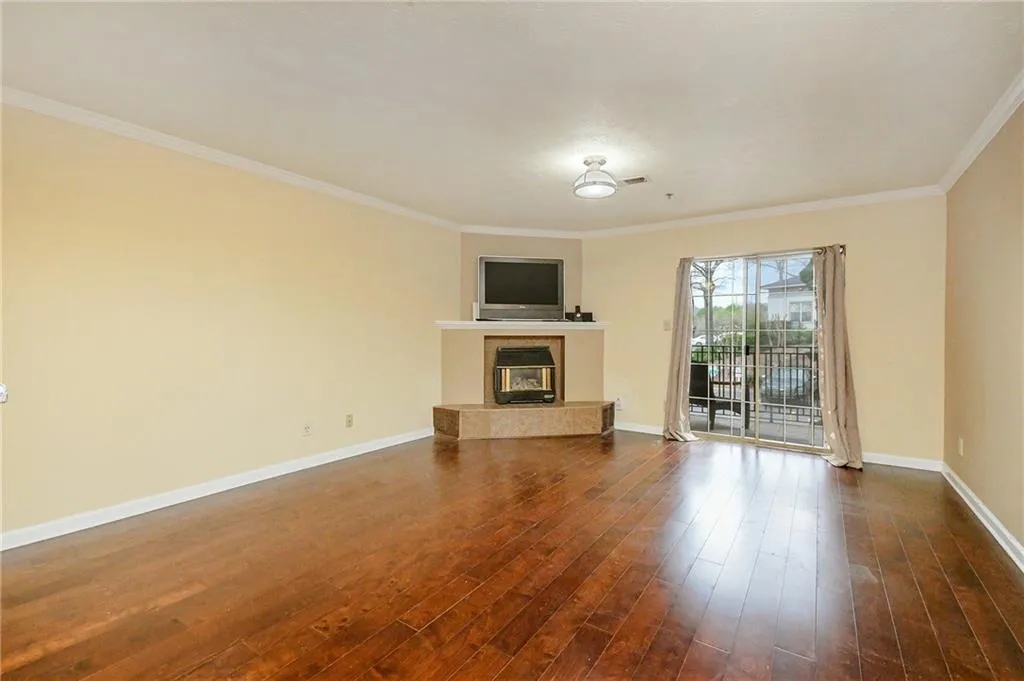 Unfurnished living room featuring a tiled fireplace, dark wood-type flooring, and baseboards