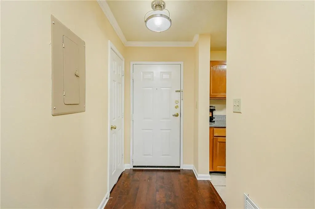Doorway to outside with visible vents, dark wood-type flooring, electric panel, crown molding, and baseboards