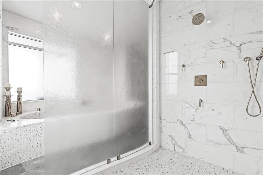 Curved, frosted glass in this oversized marble shower