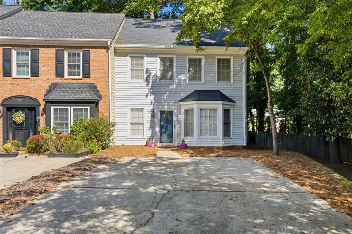 Two-story exterior with light-colored siding, bay window, and a dark asphalt shingle roof