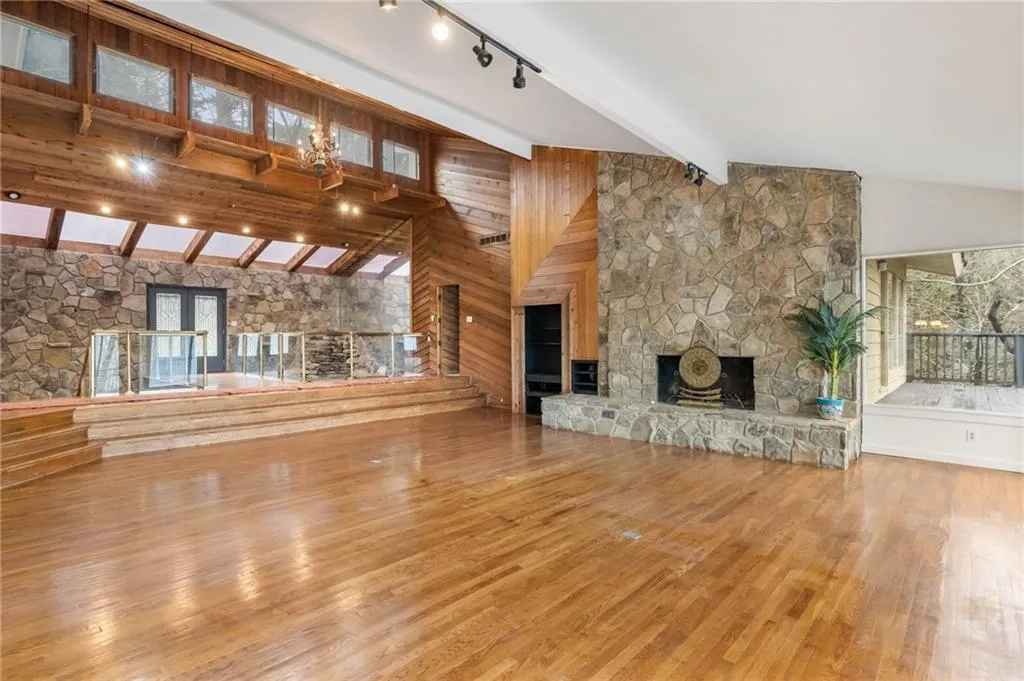 Unfurnished living room with track lighting, a fireplace, beamed ceiling, high vaulted ceiling, and light hardwood / wood-style flooring