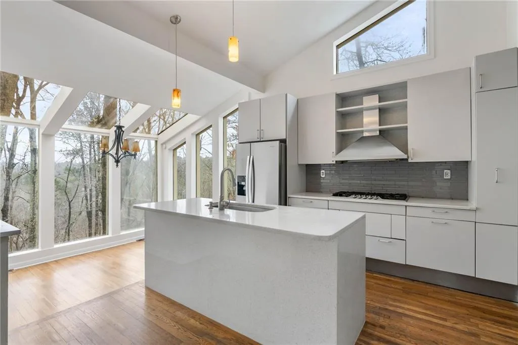 Kitchen with stainless steel appliances, vaulted ceiling, an island with sink, and a healthy amount of sunlight