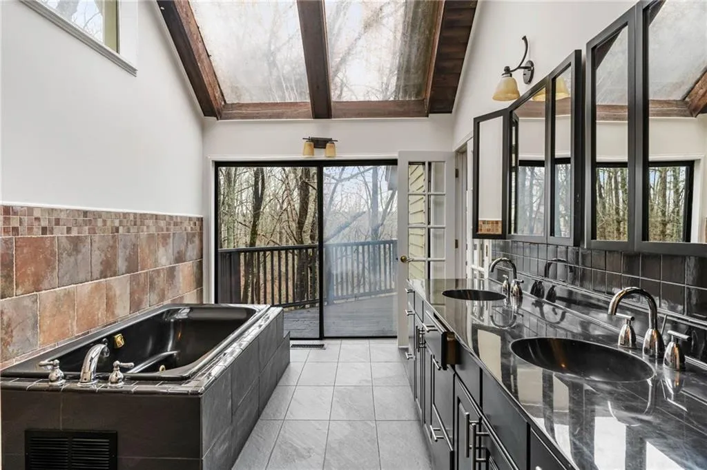 Kitchen featuring dark stone counters, sink, backsplash, and light tile floors