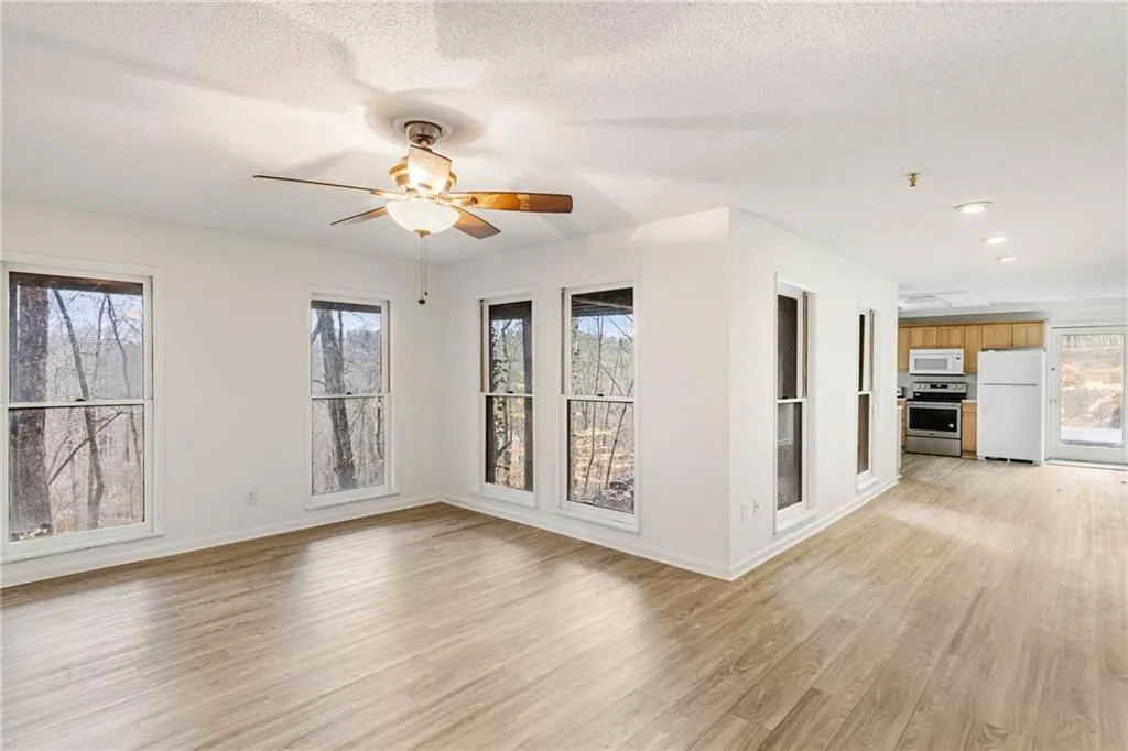 Empty room with a healthy amount of sunlight, ceiling fan, and light hardwood / wood-style flooring