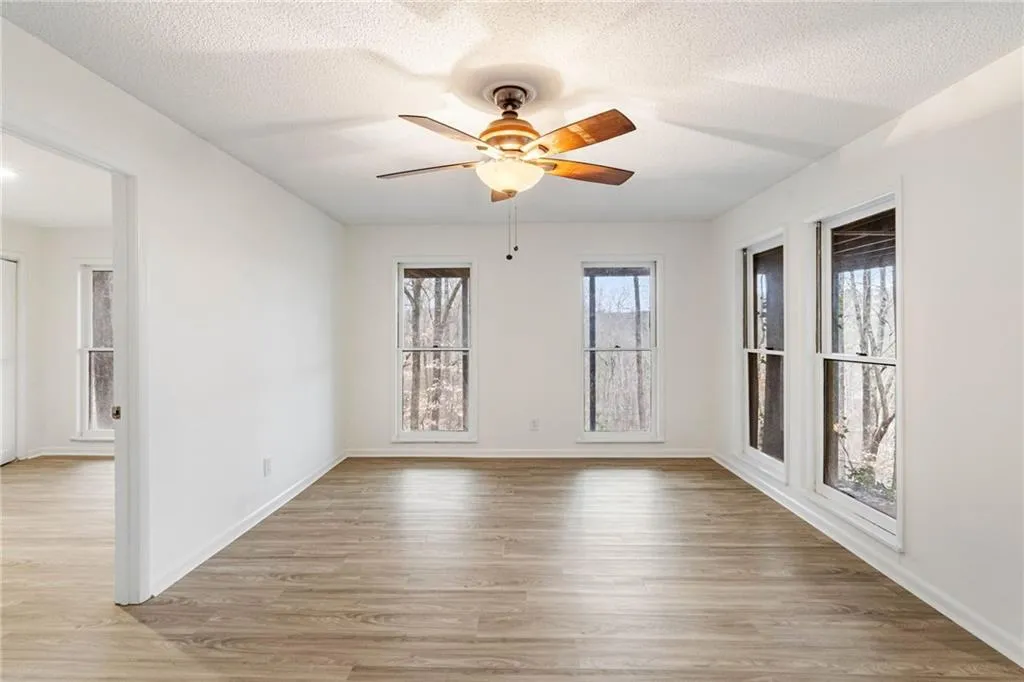 Spare room with ceiling fan, light wood-type flooring, and a textured ceiling