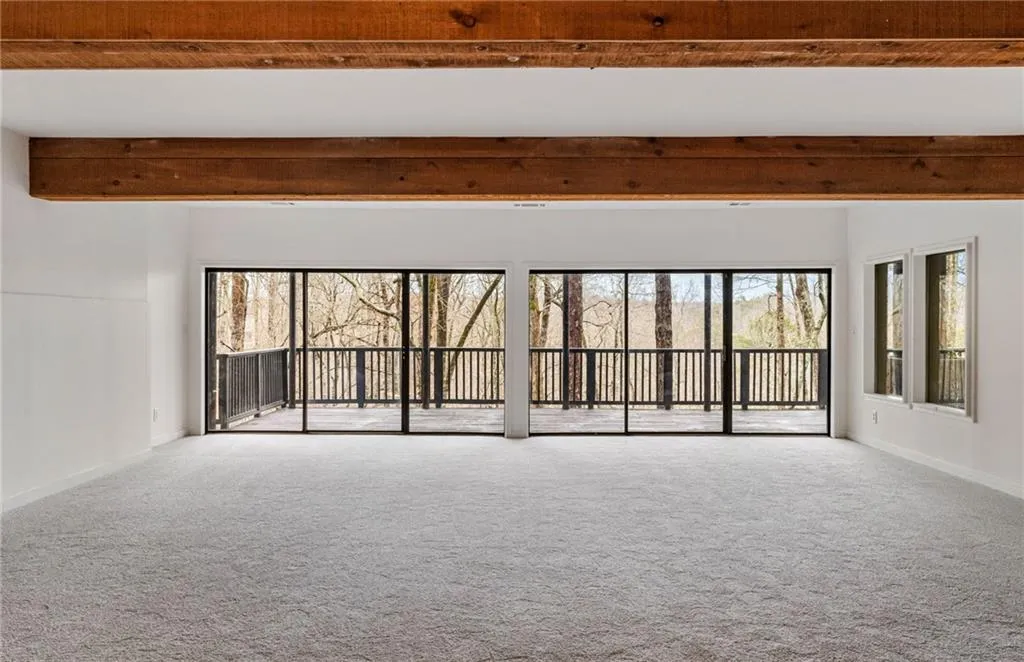 Carpeted empty room with beamed ceiling