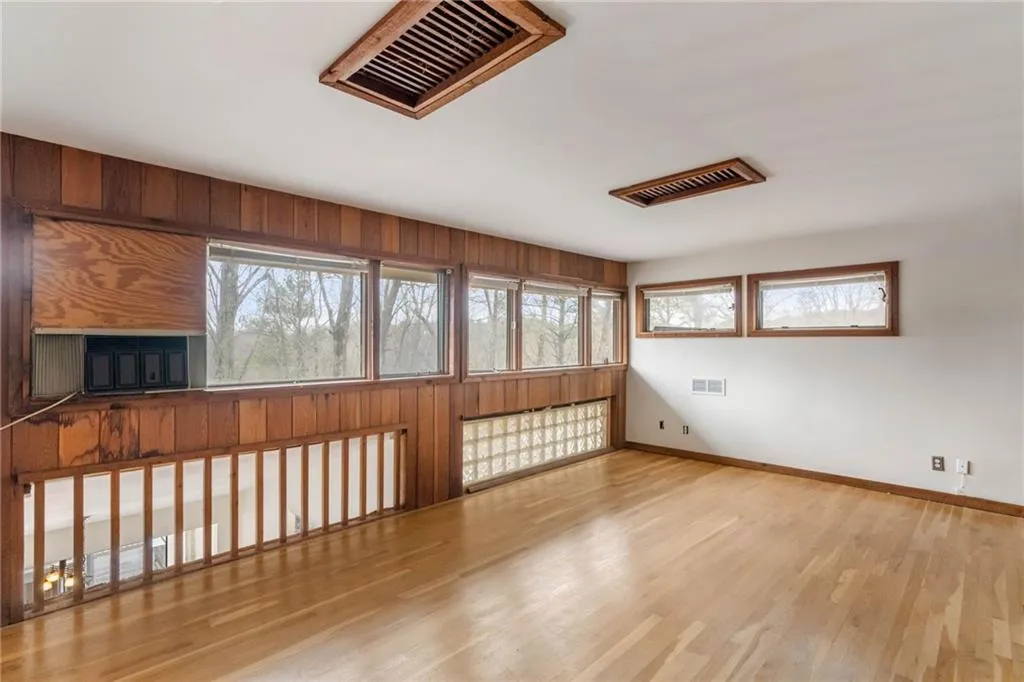 Unfurnished room featuring light wood-type flooring and wooden walls