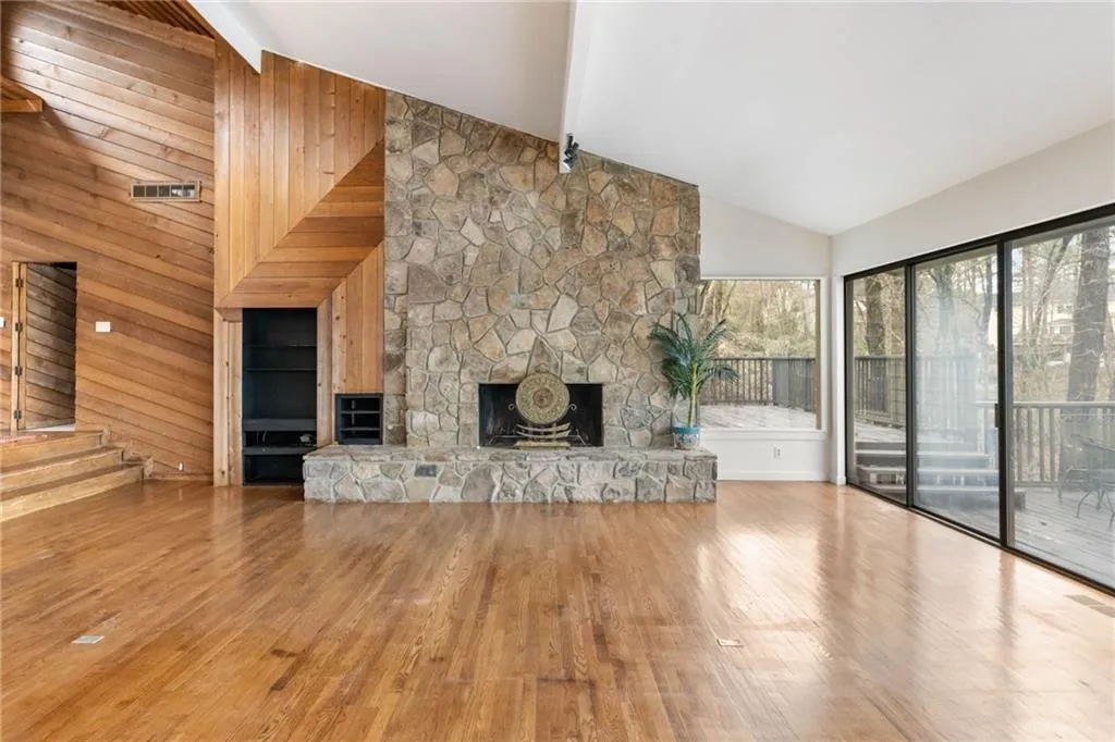 Unfurnished living room with light hardwood / wood-style flooring, high vaulted ceiling, beamed ceiling, and a fireplace