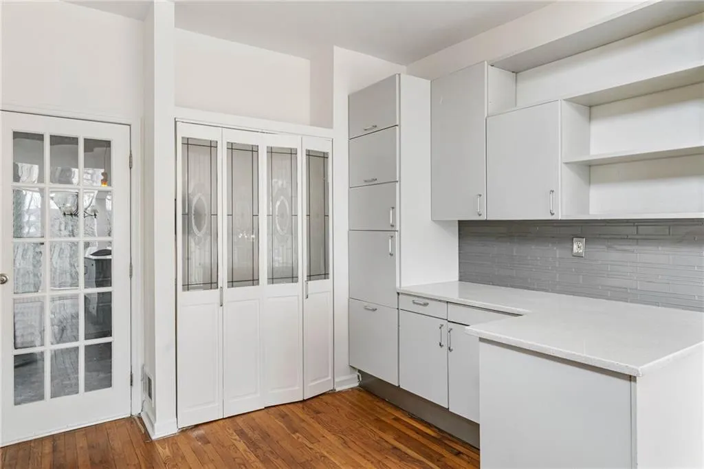 Kitchen with backsplash, white cabinets, and dark wood-type flooring