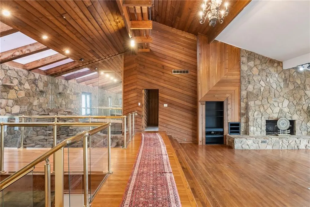 Hallway featuring beam ceiling, light hardwood / wood-style flooring, wooden walls, and a notable chandelier