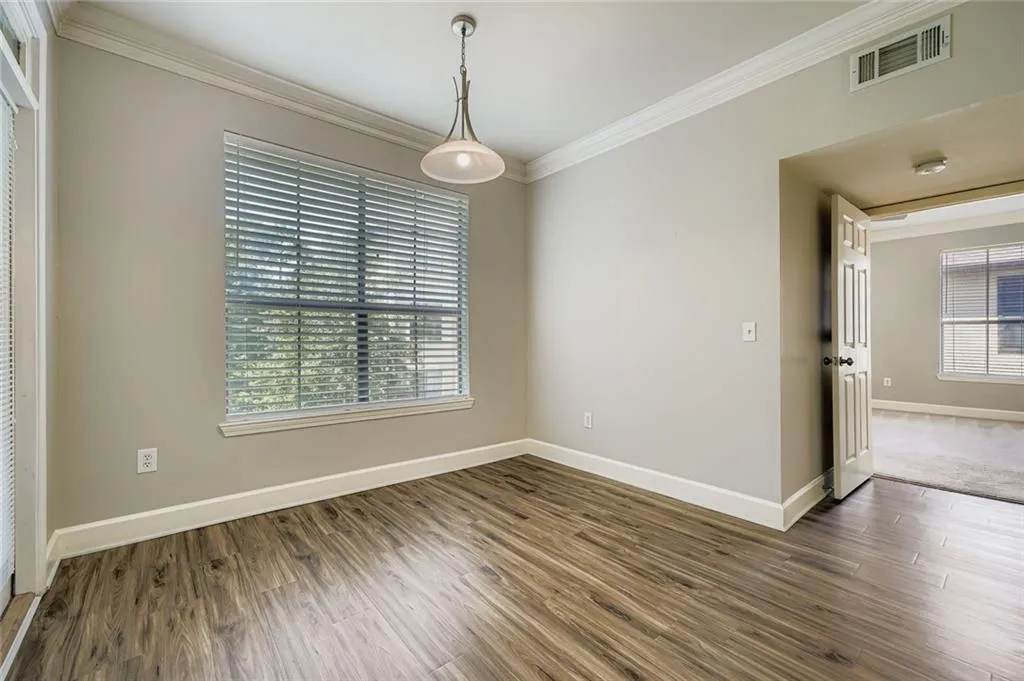 Spare room with ornamental molding, plenty of natural light, and wood finished floors