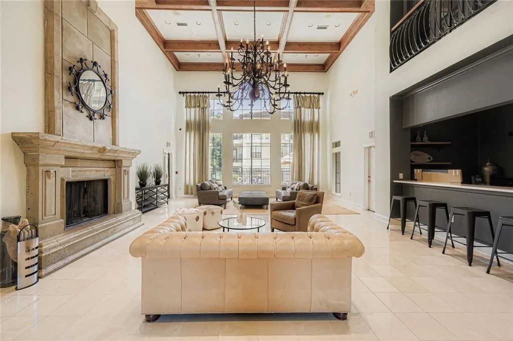 Living room with coffered ceiling, beamed ceiling, a high end fireplace, light tile patterned floors, and a chandelier