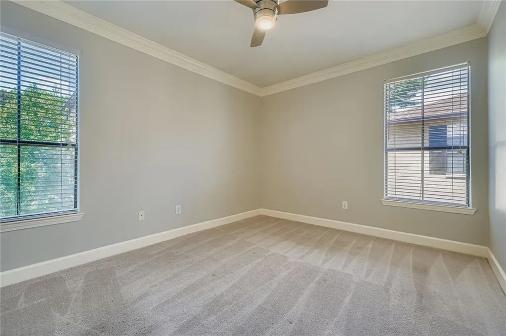 Spare room with crown molding, light carpet, and ceiling fan