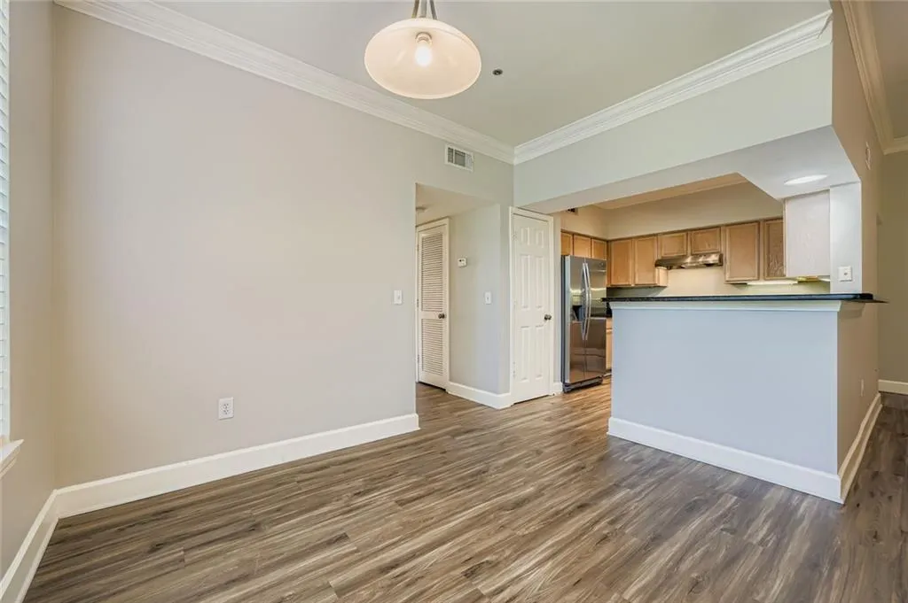 Kitchen featuring dark countertops, ornamental molding, wood finished floors, stainless steel fridge with ice dispenser, and under cabinet range hood