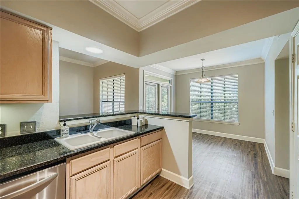 Kitchen featuring crown molding, light wood finished floors, dishwasher, light brown cabinetry, and dark stone countertops