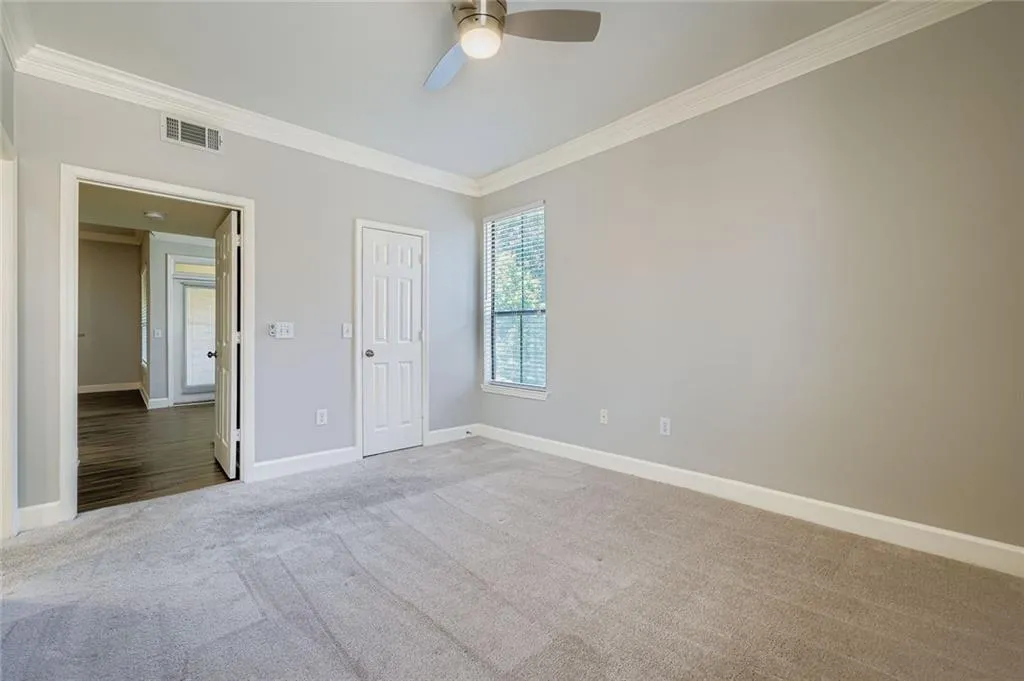 Carpeted spare room featuring ornamental molding and a ceiling fan