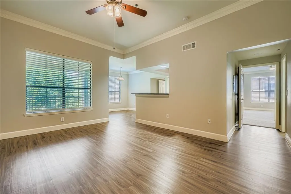 Empty room featuring ornamental molding, wood finished floors, and a ceiling fan