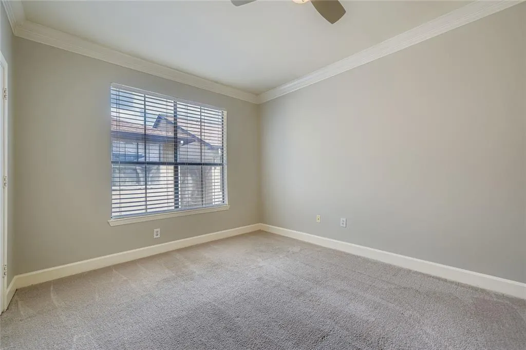 Carpeted empty room with ornamental molding and a ceiling fan