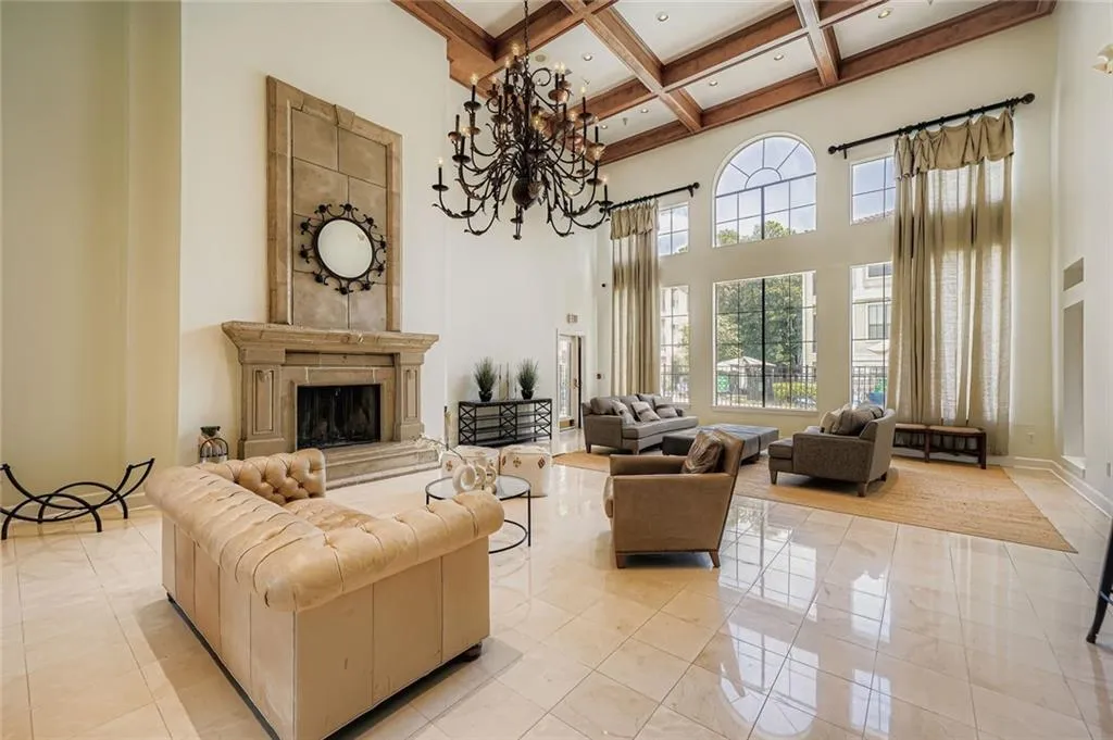 Living area featuring coffered ceiling, beam ceiling, light tile patterned floors, a fireplace, and a chandelier