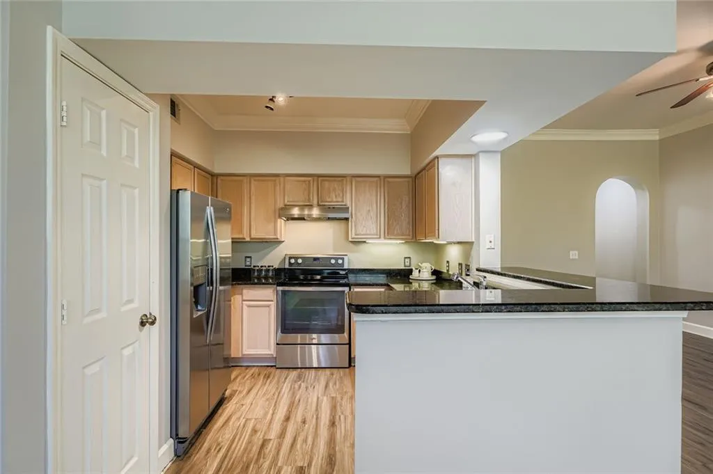 Kitchen featuring ornamental molding, appliances with stainless steel finishes, light wood-style flooring, arched walkways, and a peninsula