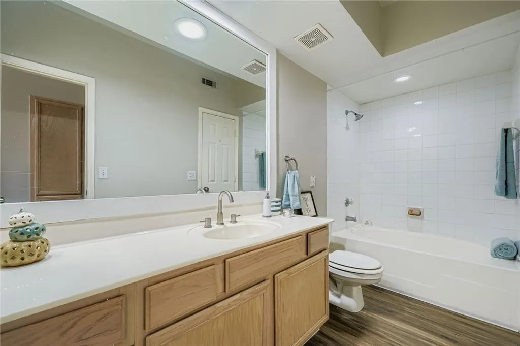 Full bath featuring vanity, wood finished floors, washtub / shower combination, and recessed lighting