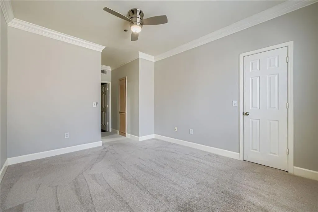 Carpeted empty room featuring crown molding and a ceiling fan