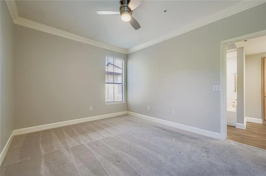 Spare room with light carpet, ornamental molding, and a ceiling fan