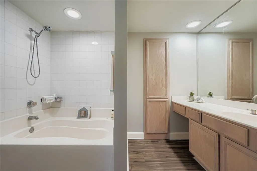 Bathroom featuring vanity, washtub / shower combination, recessed lighting, and wood finished floors