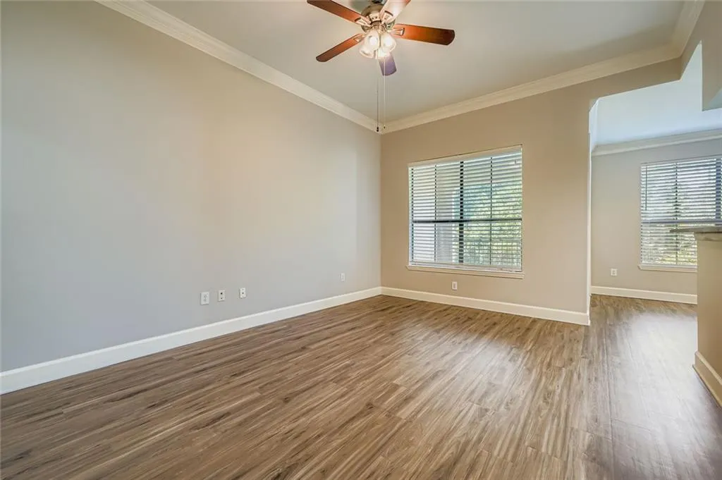 Spare room with wood finished floors, ornamental molding, healthy amount of natural light, and a ceiling fan