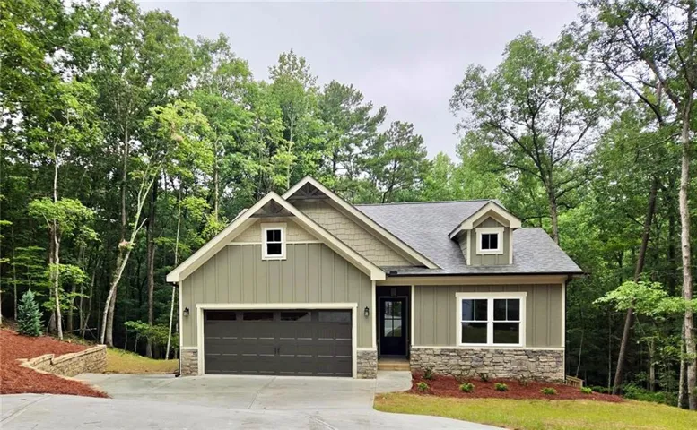 Craftsman-style exterior featuring durable siding, stone accents, a dark garage door, and a prominent front door