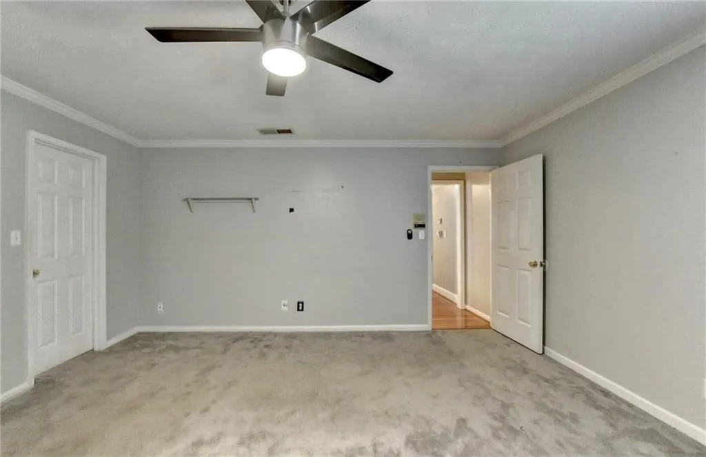 Unfurnished bedroom with carpet floors, crown molding, baseboards, and a ceiling fan