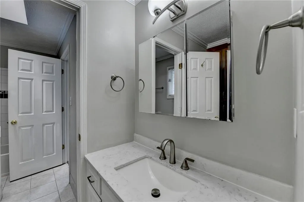 Full bath with ornamental molding, a textured ceiling, tile patterned floors, and vanity