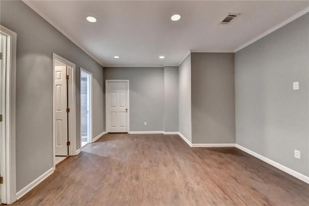 Basement open space baseboards, recessed lighting, wood finished floors, and crown molding