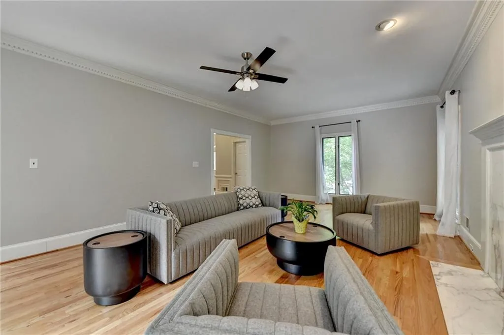 Living area with ceiling fan, wood finished floors, ornamental molding, and baseboards