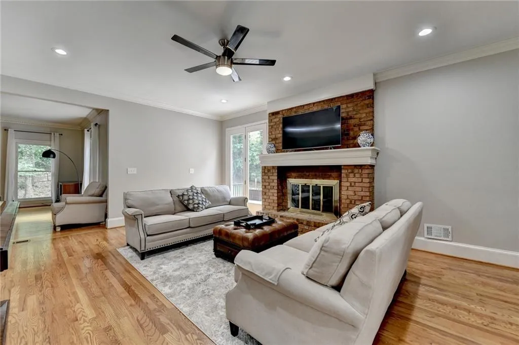 Living room with ceiling fan, plenty of natural light, light wood-style flooring, ornamental molding, and baseboards